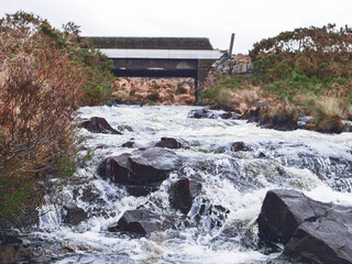 Wall Mural - a river with a bridge in the background. the water is rushing and the rocks are scattered throughout