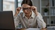 © YUSUF - Tired Businesswoman Adjusting Glasses at Desk, Eye Strain and Fatigue