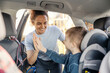 © Dusan Petkovic - Portrait of a young mom giving high five to her son while he is sitting in child seat in a car.