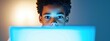 © Exnoi - Focused Young Boy Engaged with Laptop Screen in Low Light Setting