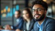 © Endin - Smiling businessman in glasses with colleagues in background.