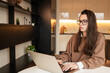 © Cavan - Woman wearing glasses working on laptop in their livingroom