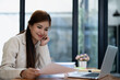 © Jirapong - Confident business woman smiling Show successful gestures at her desk with market charts and documents in office