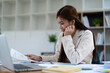 © Jirapong - Confident business woman smiling Show successful gestures at her desk with market charts and documents in office