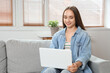 © Pixel-Shot - Young pretty woman sitting on sofa and using laptop in light living room