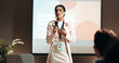 © peopleimages.com - Woman, presentation and talking at conference with mic, speech and info for employee health program. Person, public speaking and advocacy for staff wellness, audience and board at corporate seminar