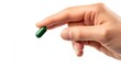 © rehan - A person is holding a single green capsule between fingers