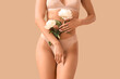 © Pixel-Shot - Beautiful young woman in stylish underwear with peonies flowers on beige background, closeup