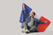 © Pixel-Shot - Young man with flag of France sitting on grey background