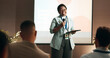 © KayExam/peopleimages.com - Business woman, workshop and training for speaker in seminar room for wellness presentation. Conference, forum speech and microphone with corporate coach on stage for public relations or development