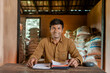 © Webbicles - a smiling man is sitting at a desk in a warehouse, surrounded by sacks of goods
