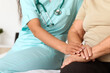 © Pixel-Shot - Young nurse with senior patient holding hands in hospital room, closeup