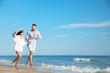 © New Africa - Happy young couple running together on beach
