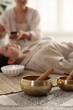 © New Africa - Woman undergoing singing bowl therapy indoors, selective focus