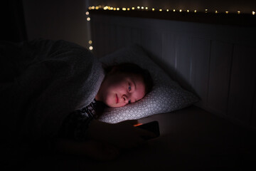 Girl using smart phone while lying on bed in bedroom