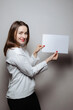 © Maksym - Smiling Woman Holding a Blank Sign in a Minimalist Studio Setting