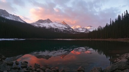 Wall Mural - colorful sunset over snow-capped mountains with reflection in the lake at the rocky shore of the val
