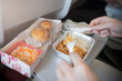 © Vladimir Razgulyaev - Close-up of a passenger enjoying a meat and chicken lunch on an airplane, hands holding a fork and knife, savoring in-flight dining experience