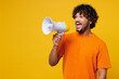 © ViDi Studio - Young happy Indian man he wearing orange t-shirt casual clothes hold in hand megaphone scream announces discounts sale Hurry up isolated on plain yellow background studio portrait. Lifestyle concept.