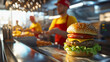 © URRMInc - A fast-food worker in a red and yellow uniform stands behind the counter, efficiently preparing a burger with fresh lettuce and tomato, while the busy kitchen staff moves quickly in the background.