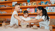 © InfiniteFlow - Handsome student dipping hand in to water to soften clay at art classroom. Group of diverse children working or modeling vase. Happy boy put water to young girl while laugh with happy. Edification.