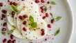 © fivan - Sliced mozzarella with pomegranate seeds and a touch of pink Himalayan salt, elegantly plated on a minimalist white background