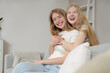 © Pixel-Shot - Beautiful young happy sisters sitting on sofa at home