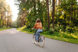 © maxbelchenko - Young modern woman rides bicycle in the park. Sports activities. Taking care of environment