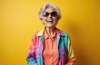 © Pete - Laughing elderly woman in colorful jacket, orange shirt, sunglasses on bright yellow background. Smiling mature lady with white hair, fashion earrings. Old age positive vibes, modern cheerful senior