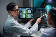 © pressmaster - Doctor explaining MRI scan results to patient while using computer technology, showing diagnostic images and discussing medical conditions in a professional healthcare setting
