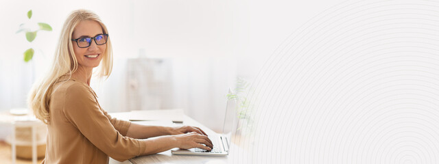 Aufkleber - A woman with long hair and glasses sits at a desk, using a laptop. The workspace features natural light and indoor plants, creating a productive and inviting atmosphere for remote work, copy space