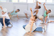 © JackF - Cheerful sports preteen girls and boys hip hop dancers doing dance workout on floor with male trainer during group class at dance studio