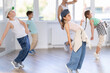 © JackF - Focused preteen girl performing dynamic hip hop moves in group class for kids, led by skilled young male dance instructor in vibrant urban studio