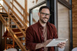 © Migma_Agency - Happy freelancer smiling and using digital tablet at home office