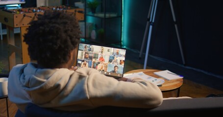 Wall Mural - focused young man smiling and waving during a web conference at his home, showcasing online communic