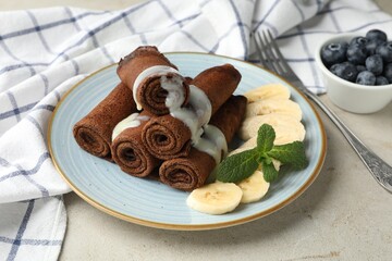 Wall Mural - delicious chocolate crepes with banana and blueberries served on light table, closeup