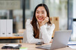 © David - Smiling business asian woman  using laptop at work document sitting in the office,