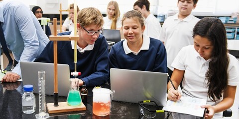 Fototapete - Students in a science class working on experiments. Diverse group, including young men and women, focused on chemistry with laptops and lab equipment. High school students in science lab classroom.