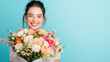 © Keopaserth - young woman smiles joyfully while holding large bouquet of colorful flowers against bright blue background, radiating happiness and warmth