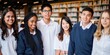 © Rawpixel.com - Group of diverse students in a library, wearing uniforms, smiling. Students in a library setting, diverse group, wearing uniforms, happy expressions. Diverse students in library, education concept.