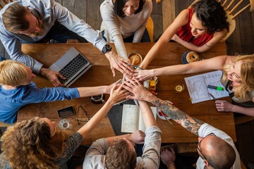 Wall Mural - diverse group of people around a table, hands together in unity. teamwork, collaboration, and unity 