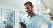 © CC/peopleimages.com - Man, phone and texting by window in office with smile, contact and notification on web at startup. Business person, smartphone or happy with mobile app, social media or networking at creative agency