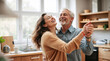 © ipolstock - Joyful middle-aged couple dancing together in bright modern kitchen for romance, relationship, love, lifestyle, retirement, and family connection concepts.