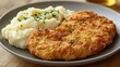 © Chandlerlikes - A golden, crispy breaded cutlet, either schnitzel or a breaded chop, served with creamy mashed potatoes, creating a classic and satisfying meal.