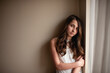 © Cavan Images - Teen girl leans on wall with neutral expression by window at home