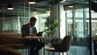 © mirifadapt - man in a blazer working on a tablet, seated at a high table with a coffee cup and notepad, in a stylish open-plan office with glass dividers and ergonomic chairs