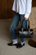 © Mykola - A girl in a white shirt blue jeans and loafers is posing with a black bag.