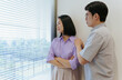 © Timeimage - Couple having a serious conversation by the window in a modern apartment during daylight hours