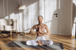 © anatoliycherkas - Young woman practicing yoga, meditating at home on a mat in a relaxing atmosphere