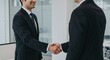 © GS-Studio - Handshake Agreement: A firm handshake seals a successful business deal, symbolizing agreement and partnership in a modern office setting.
